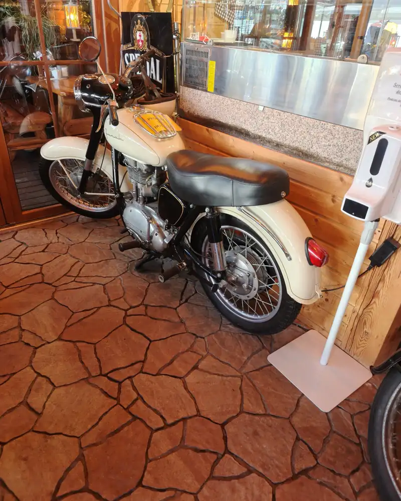 Stary motocykl ustawiony w drewnianym wnętrzu karczmy