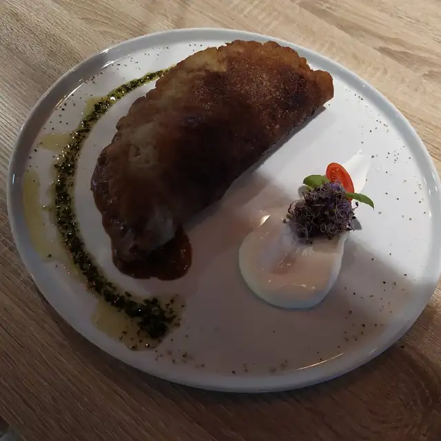 Złożony placek ziemniaczany z gulaszem, śmietaną i pesto