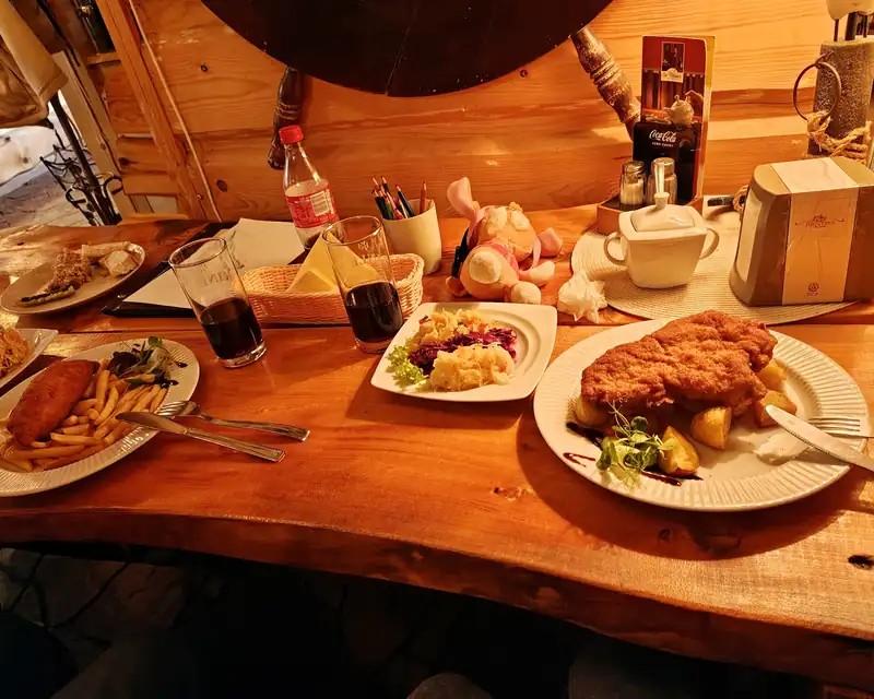 Zastawiony drewniany stół: kotlet, ryba z frytkami i surówki